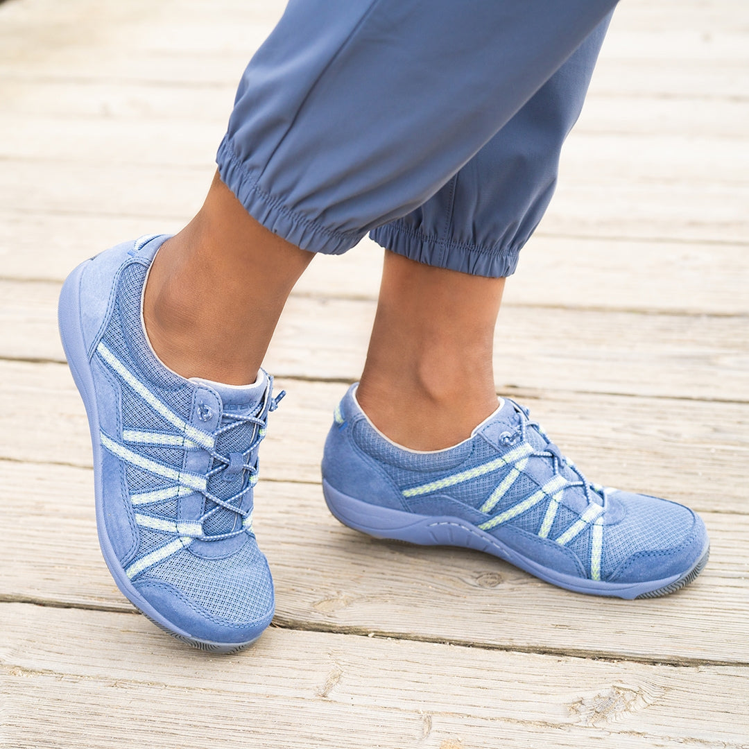 Close up of blue bungee-cord sneakers on a woman wearing blue joggers.