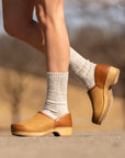 An on-foot look at fashionable tan clogs worn with wool socks