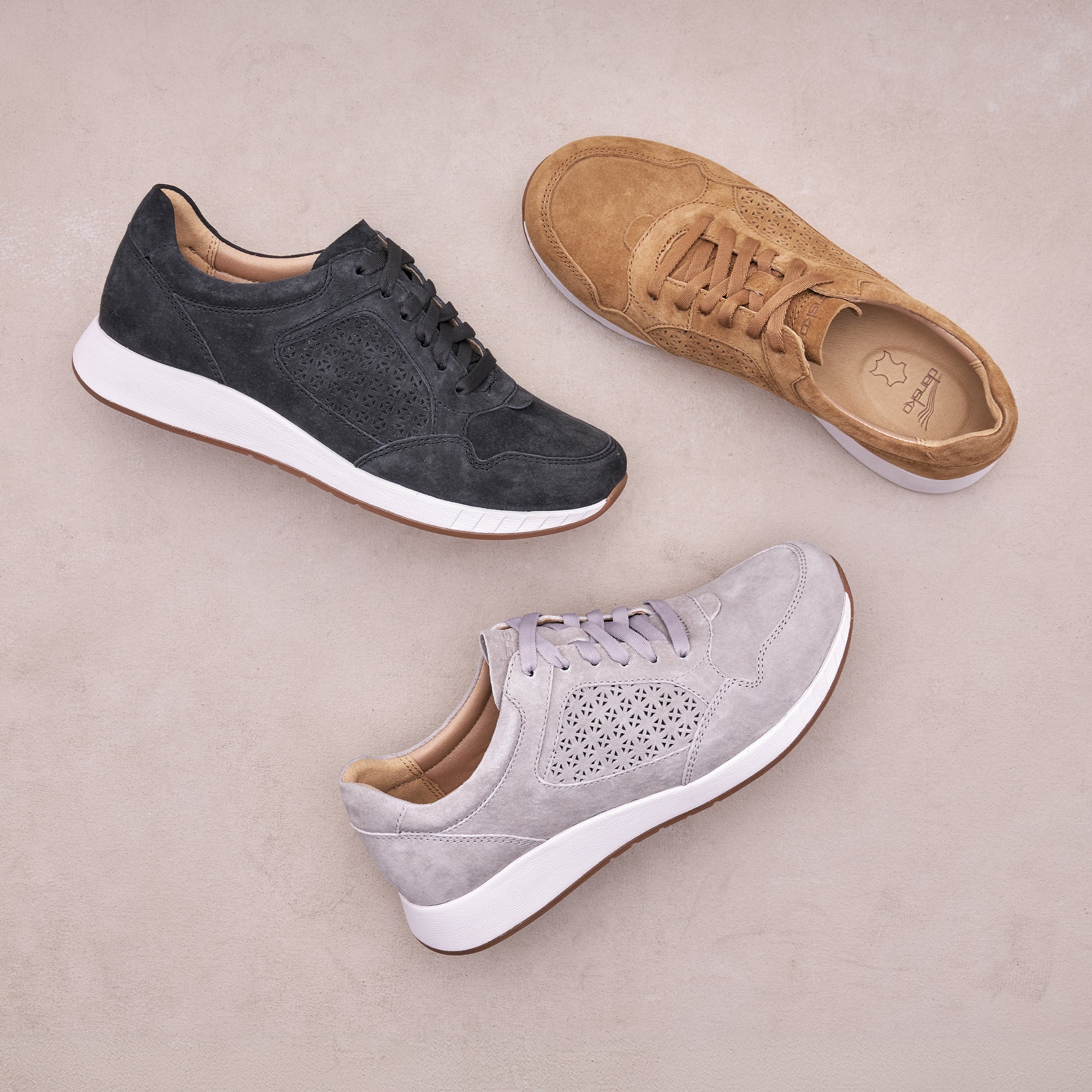 Flat lay of three different colored sneakers on a grey background.