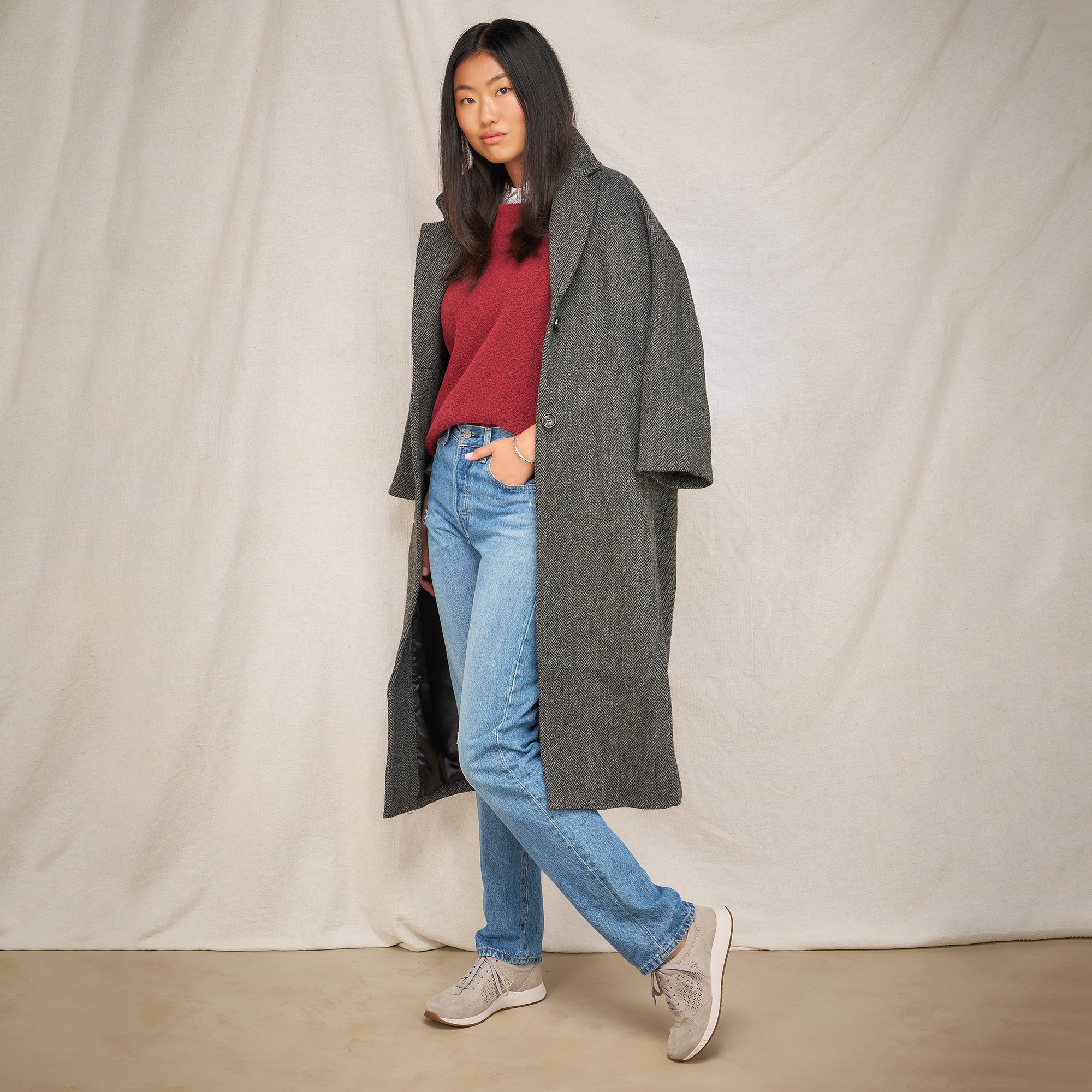 A woman in autumn attire wearing grey sneakers.
