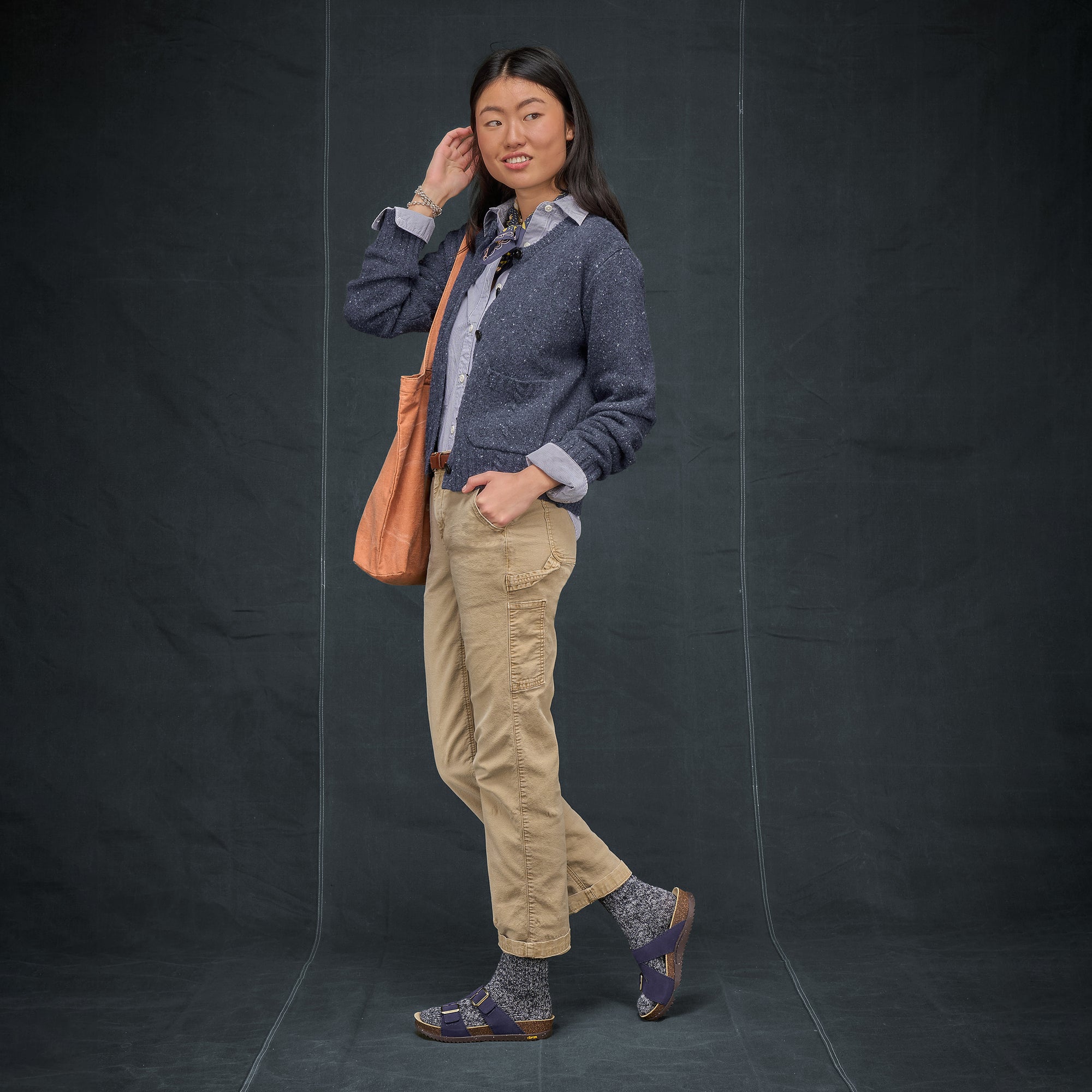 A woman dressed for work wearing navy blue slide sandals and wool socks.