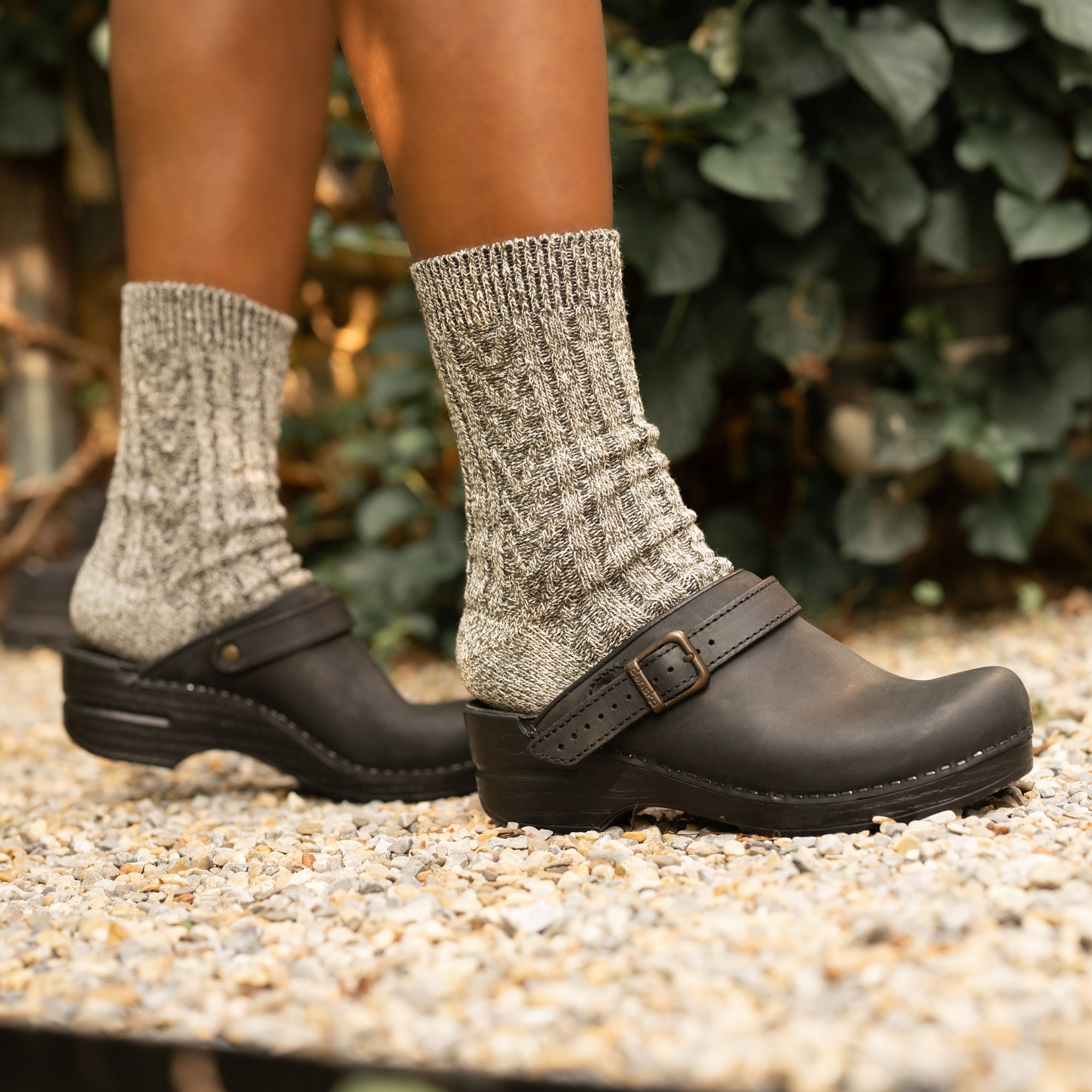 Black mule clogs with an adjustable strap styled with grey wool socks.