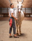 A woman working with a horse while wearing supportive brown clogs.