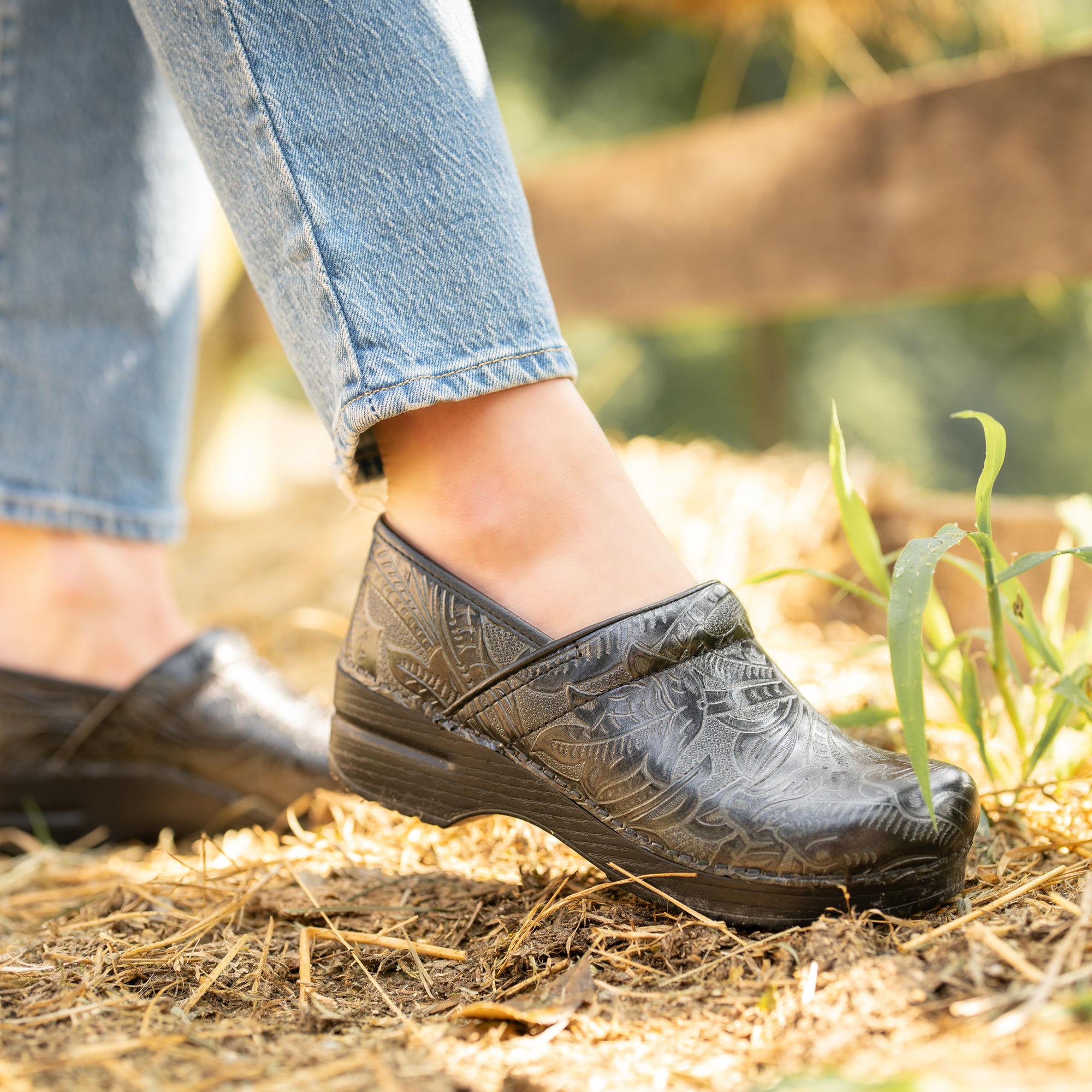 Black clogs with a flower pattern styled with light jeans.