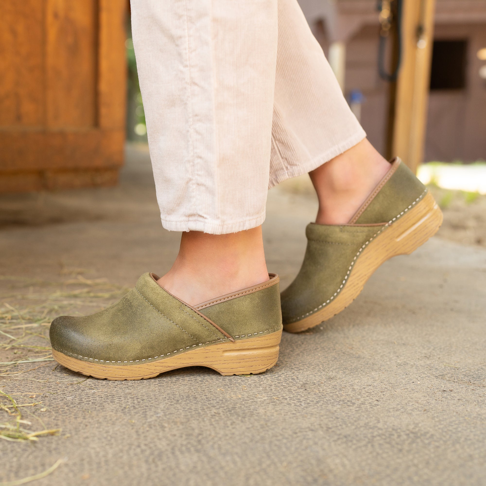 Green comfort clogs in a barn setting.