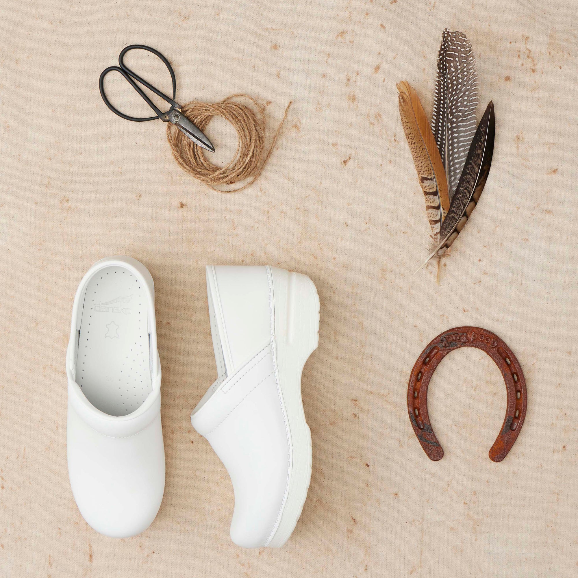 Stylish white clogs shown with barn materials.