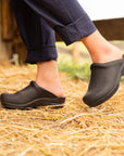 Brown mule clogs from Dansko shown in a barn setting.