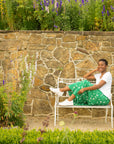 A woman on a bench in a casual skirt and t shirt wearing lightweight white leather sneakers.