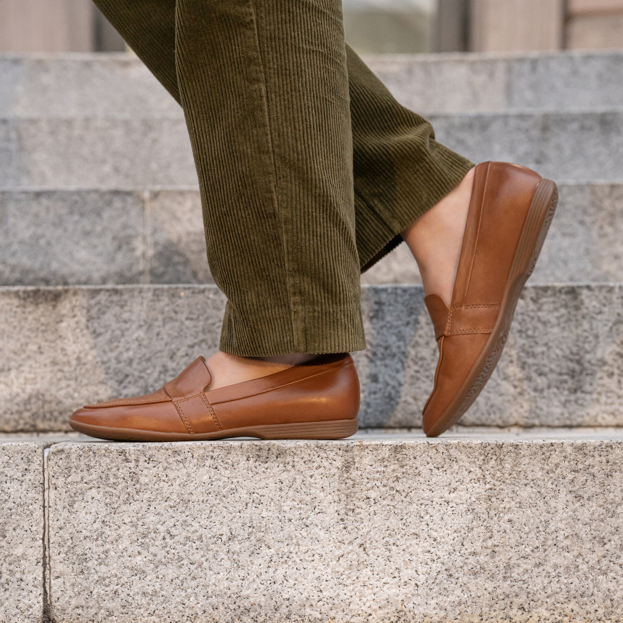 Brown leather flat loafers shown on foot.