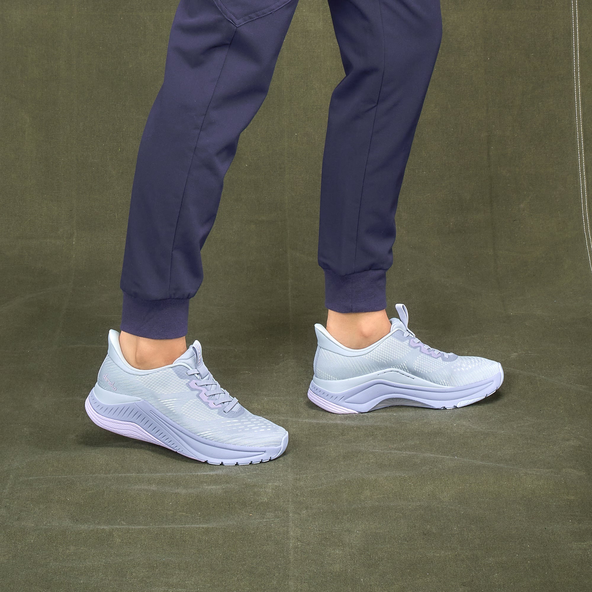 A closeup of lilac walking sneakers worn with scrubs.