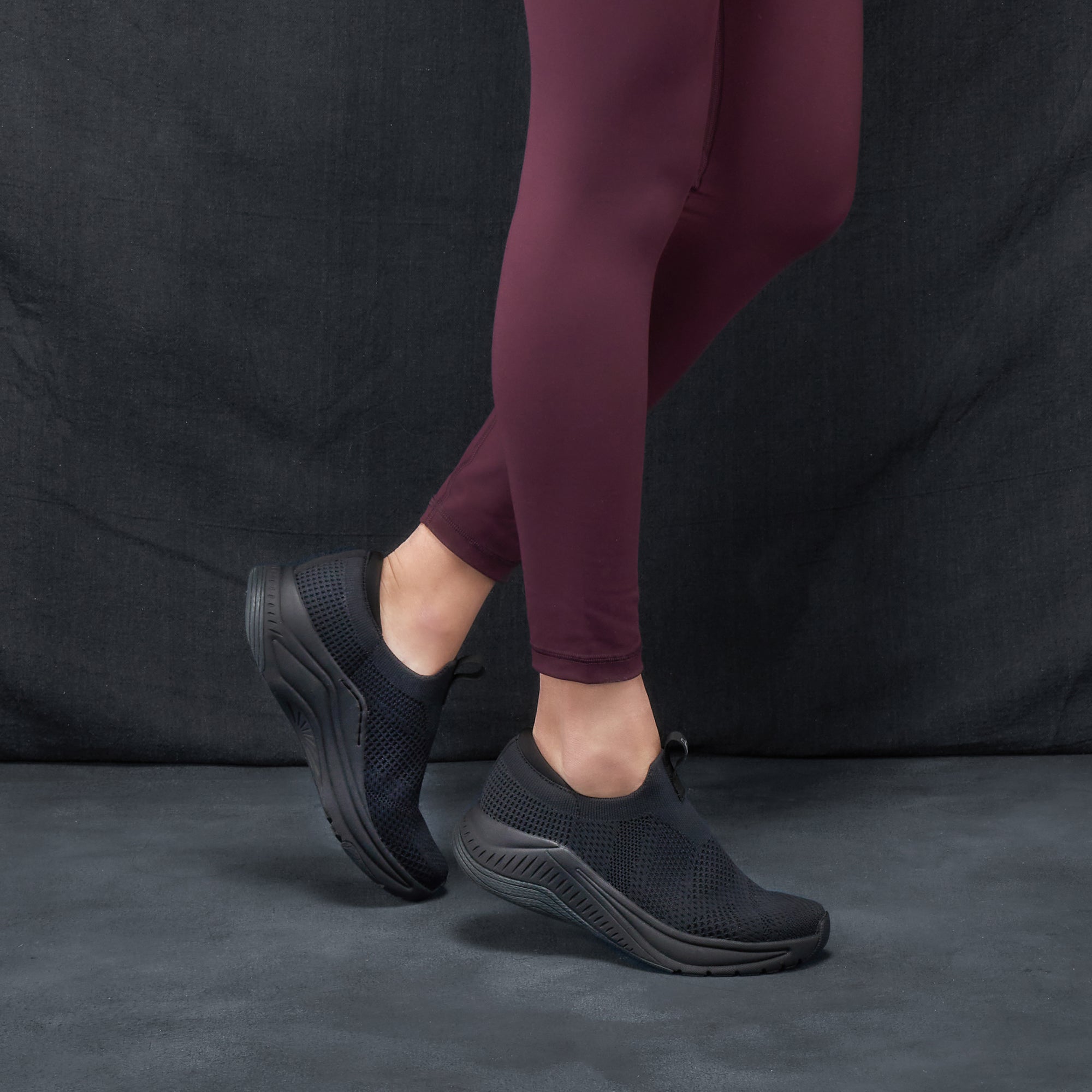 A closeup of breathable slip-on walking sneakers shown on foot.