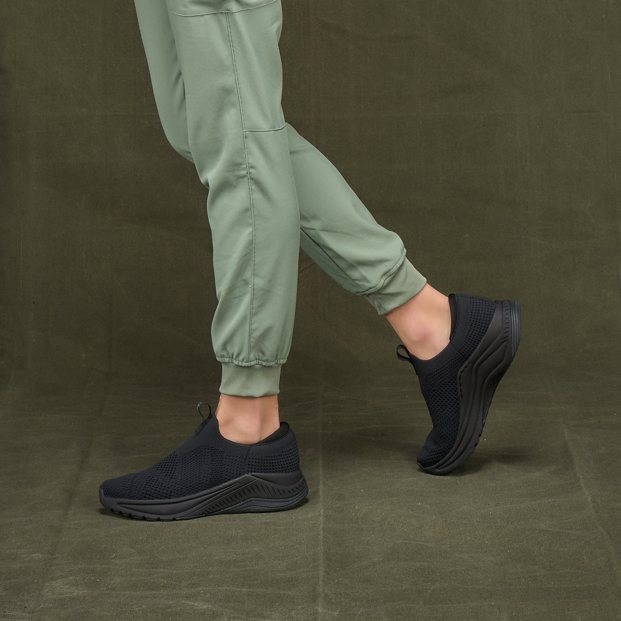 A closeup of breathable slip-on sneakers shown on foot.