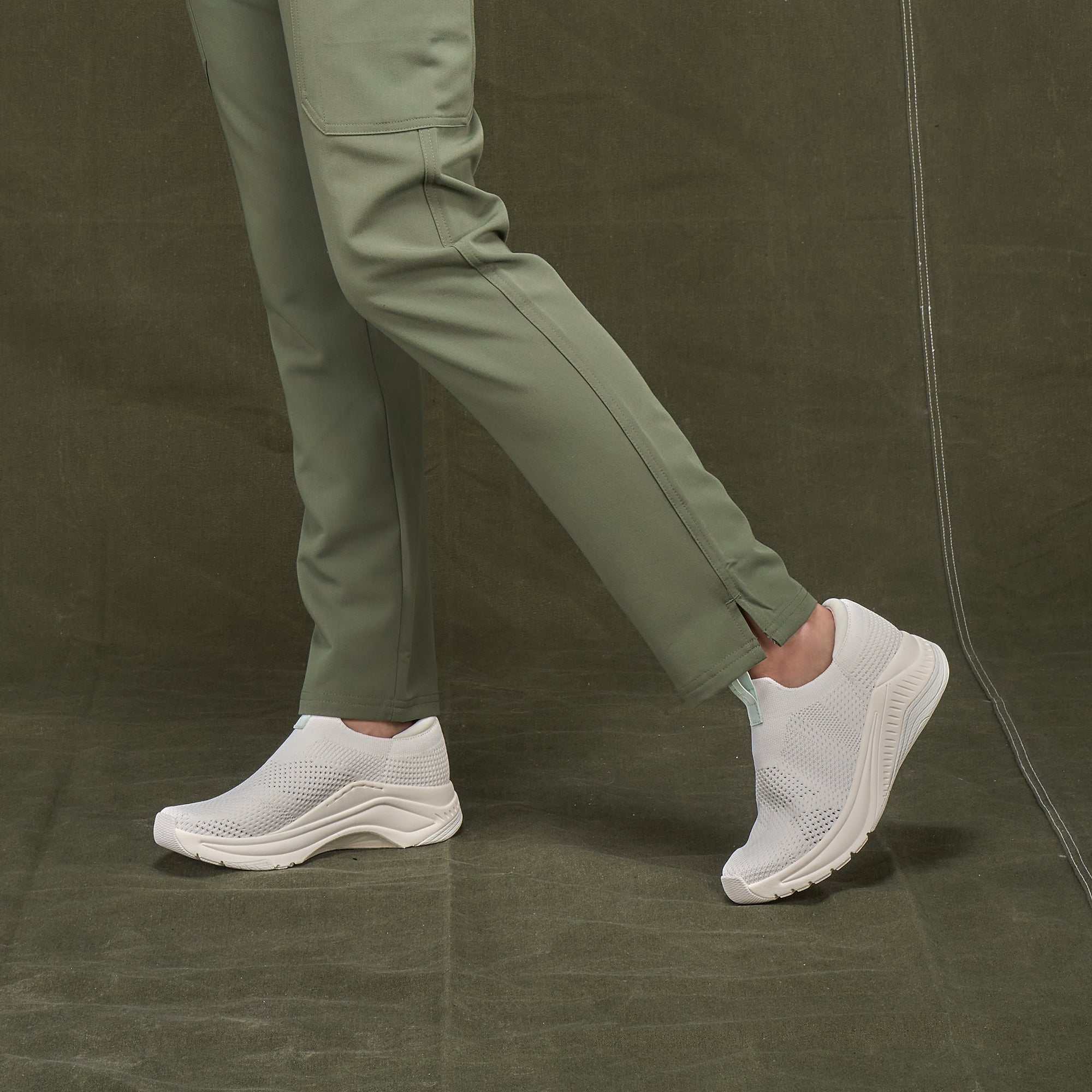 A closeup of breathable slip-on sneakers shown on foot.