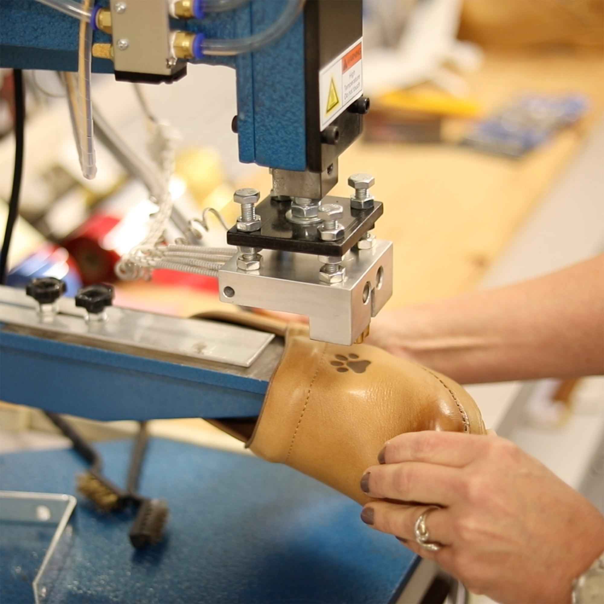 A machine personalizing a pair of clogs with a dog paw.