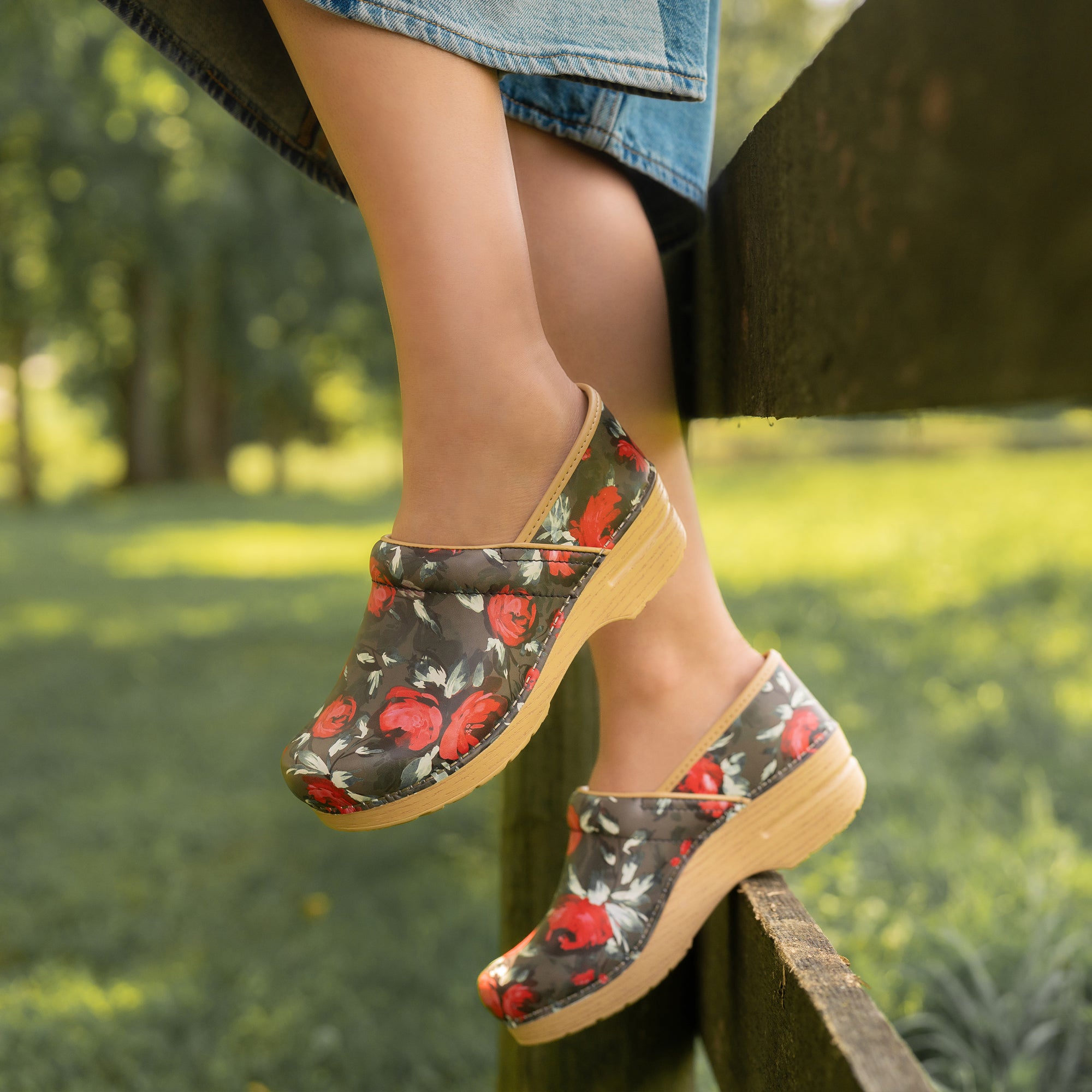 Floral-patterned clogs worn outdoors on a blurred natural background