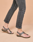 A closeup of metallic leather sandals worn with black jeans.