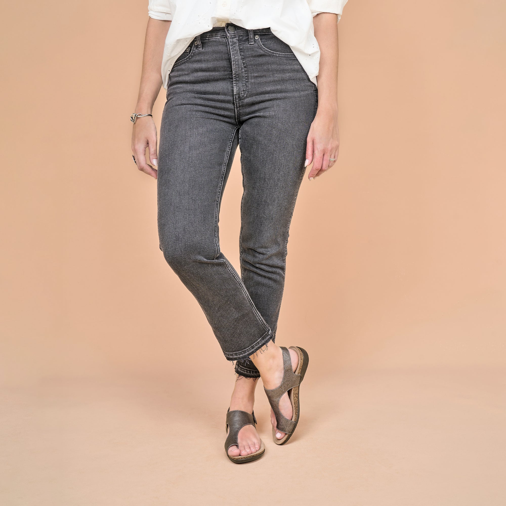 Metallic leather flat sandals shown worn with black jeans.