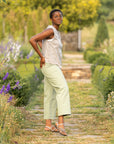 Woman in outdoor garden wearing neutral outfit with metallic strappy flat sandals.
