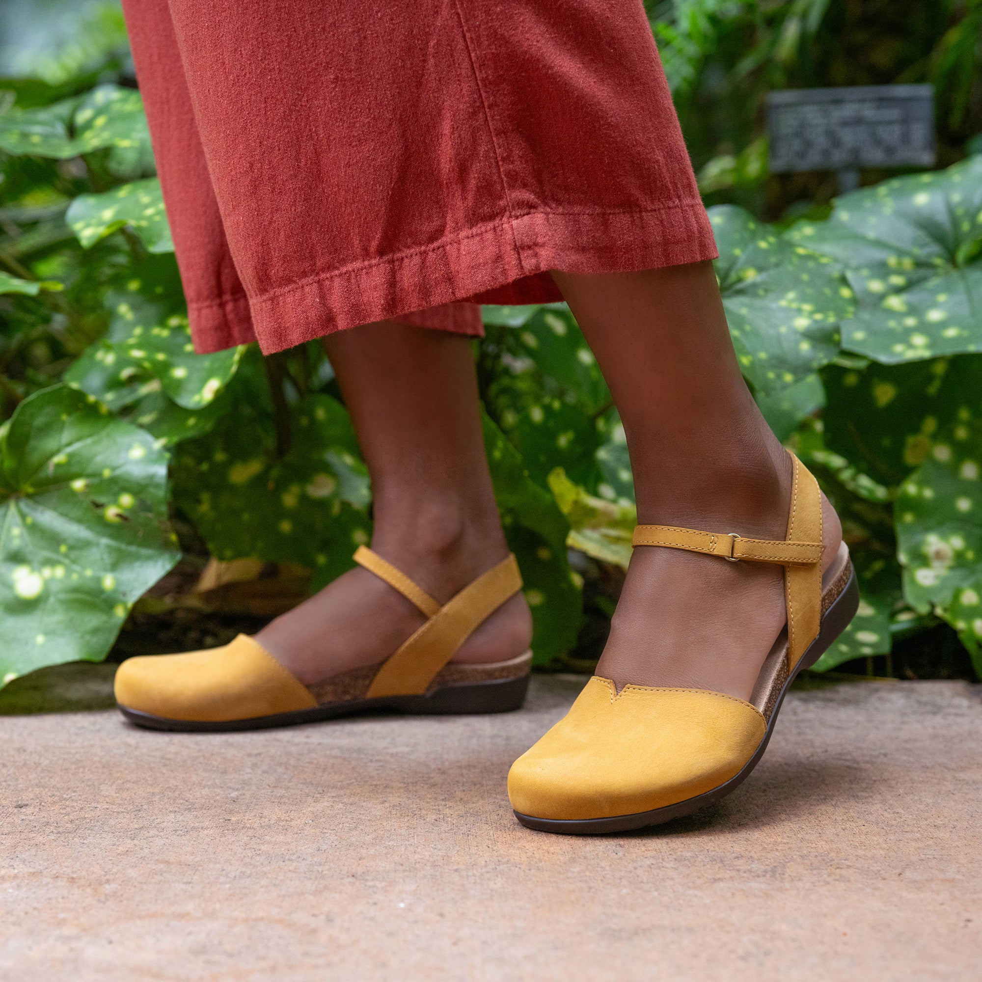 Closeup of yellow Mary Jane sandals with an adjustable ankle strap.