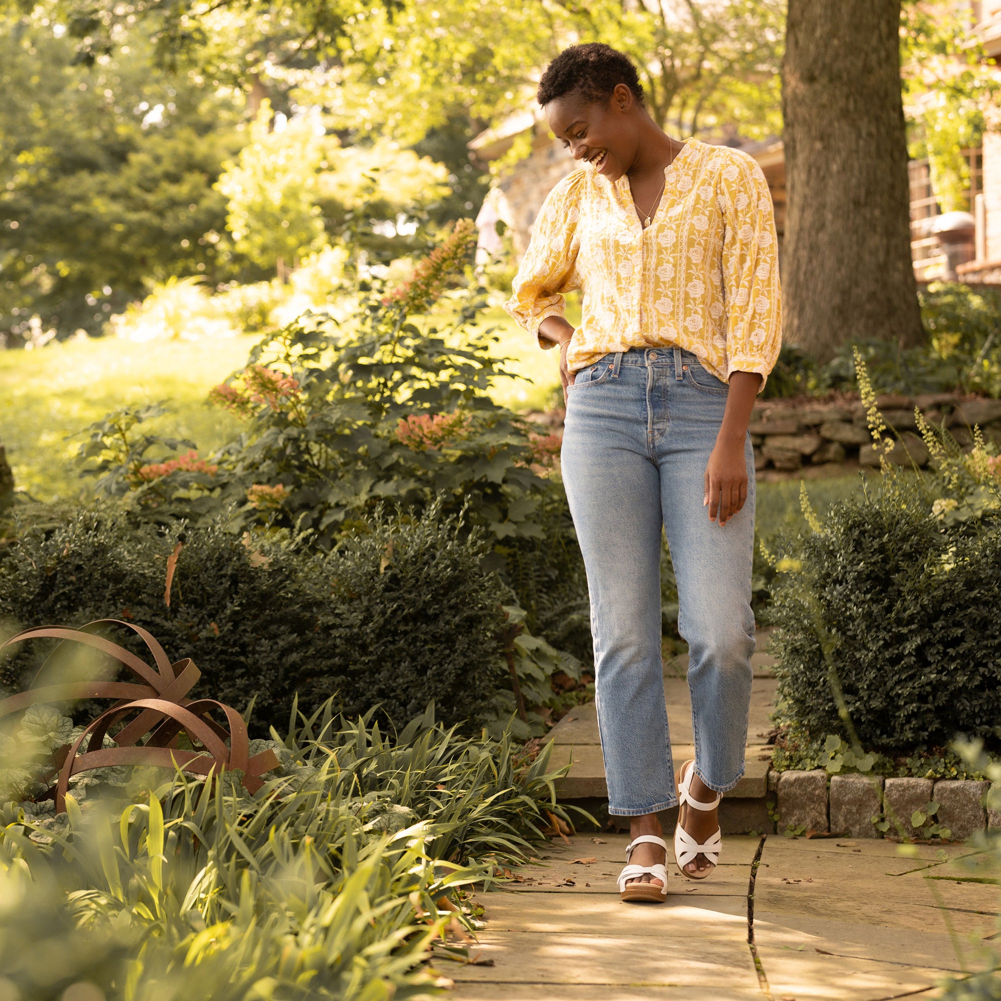 Woman standing in garden in stylish and supportive white sandals.