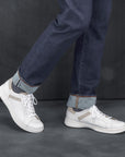 Man in jeans wearing trendy and casual white leather sneakers.