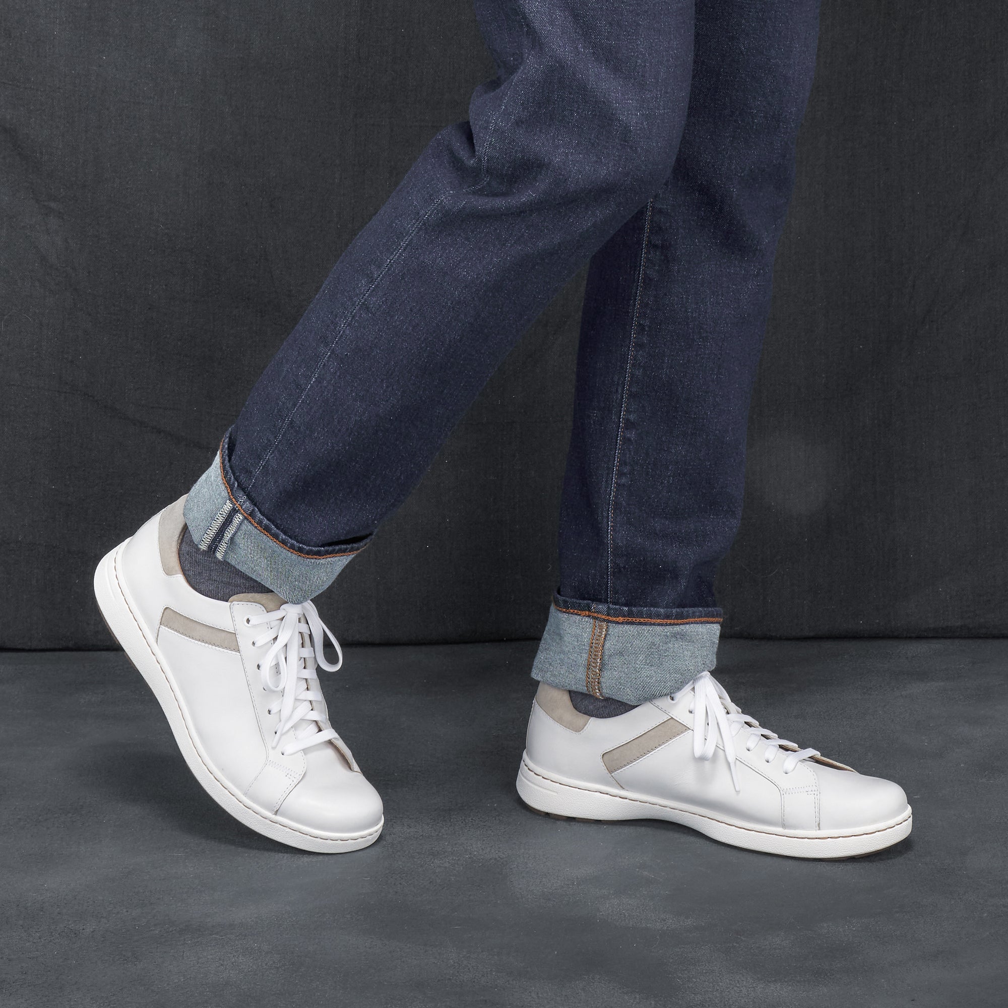 Man in jeans wearing trendy and casual white leather sneakers.
