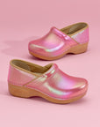 Close up of pink iridescent clogs on pink backdrop.
