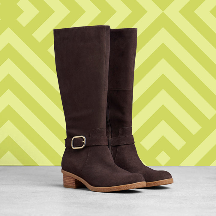Brown tall-shaft boots shown on a yellow background.