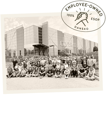 Dansko employees outside the company building with an employee-owned emblem