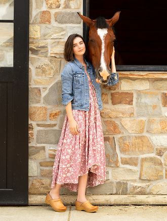 Woman wearing Dansko clogs standing beside a horse