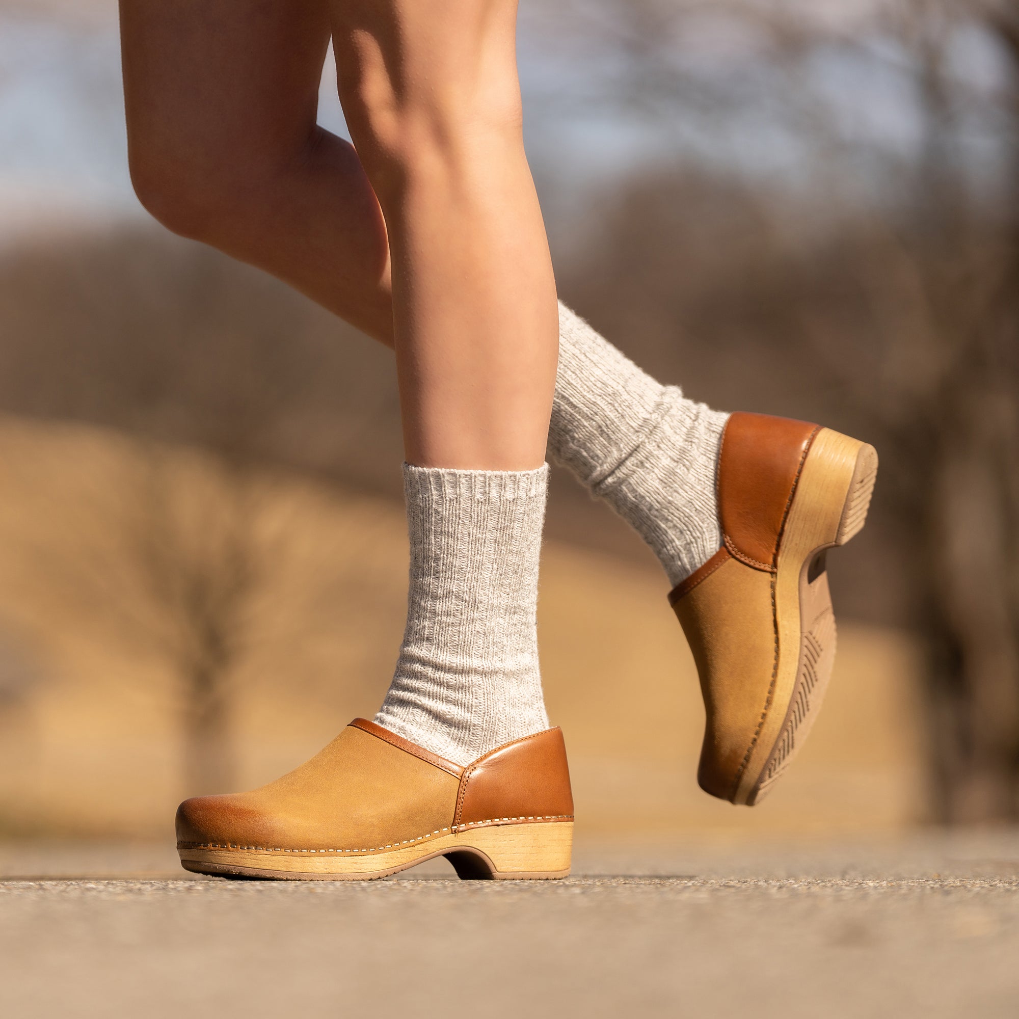 An on-foot look at fashionable tan clogs worn with wool socks