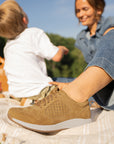 A close-up shot of a brown sneaker shown on foot.
