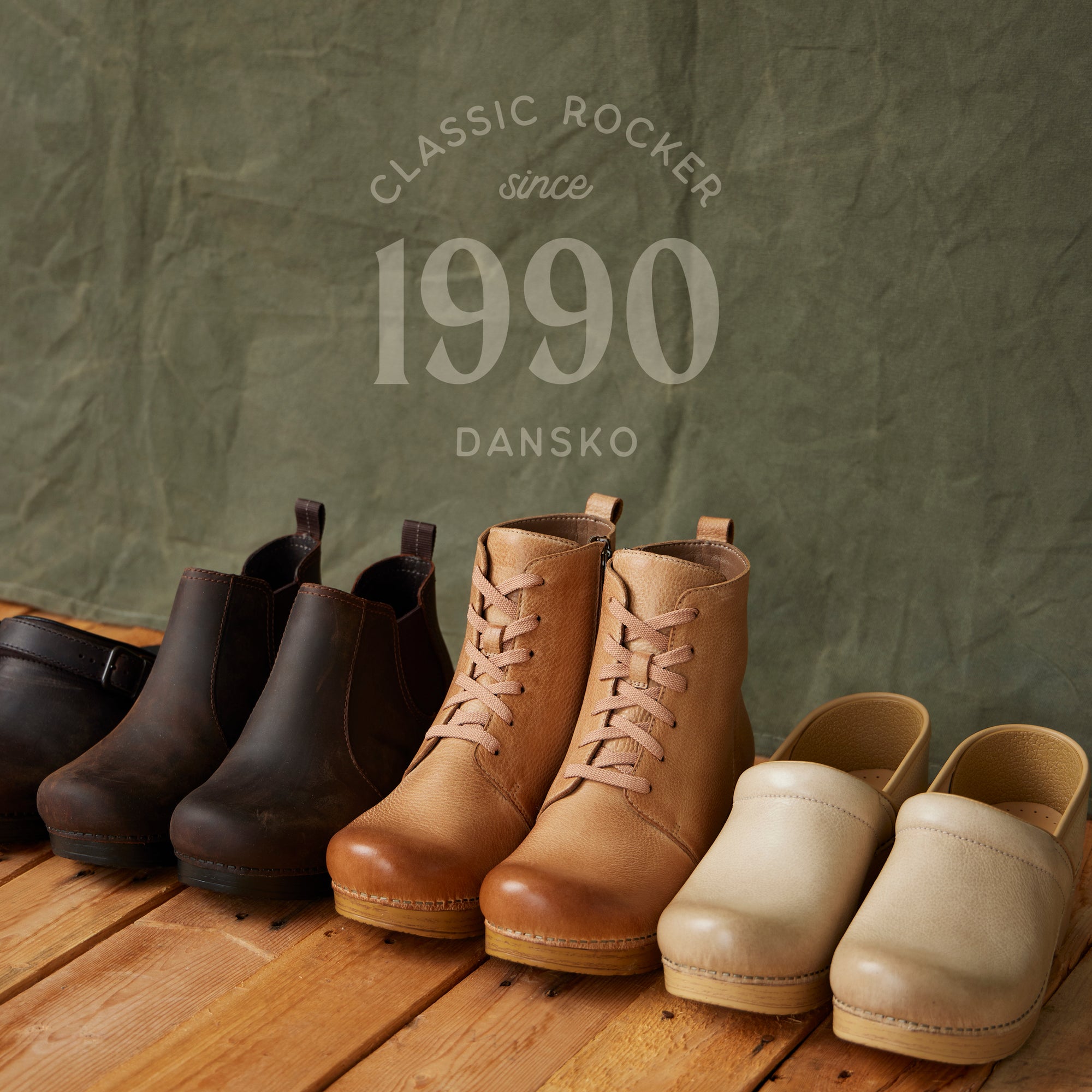 Classic Dansko shoes lined up on hardwood floor in front of dark neutral backdrop. The backdrop has text overlay that reads: Classic Rocker since 1990 Dansko"