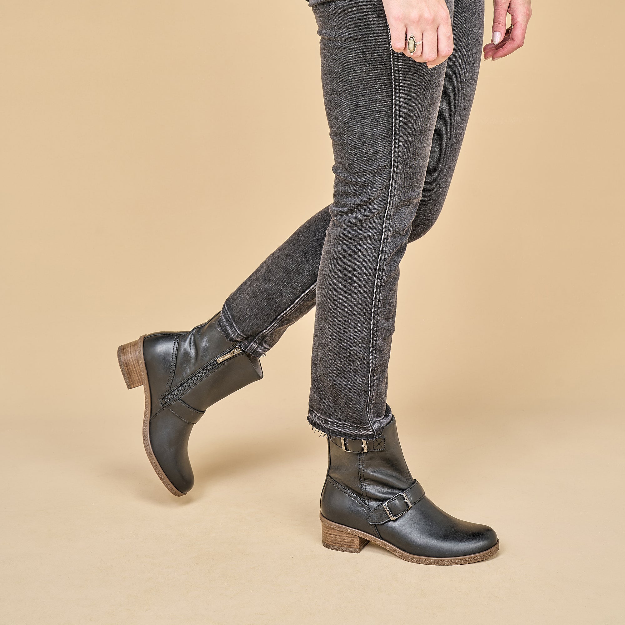 An on-foot look at black biker booties with stylish hardware and durable leather outsoles.