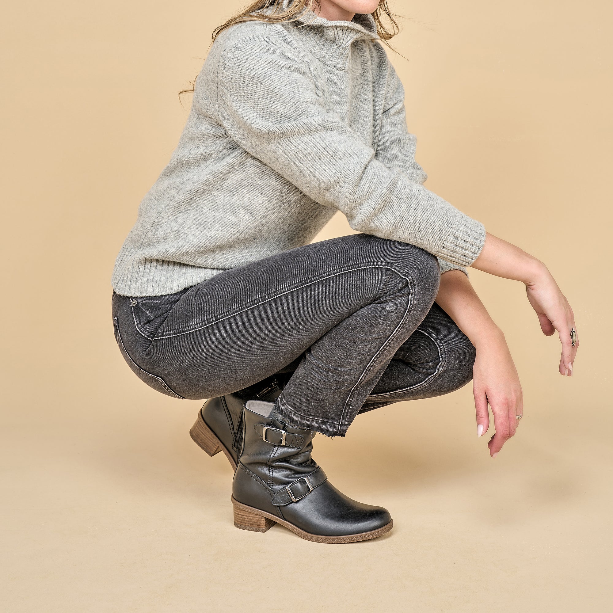 A woman in fall attire wearing black biker booties.