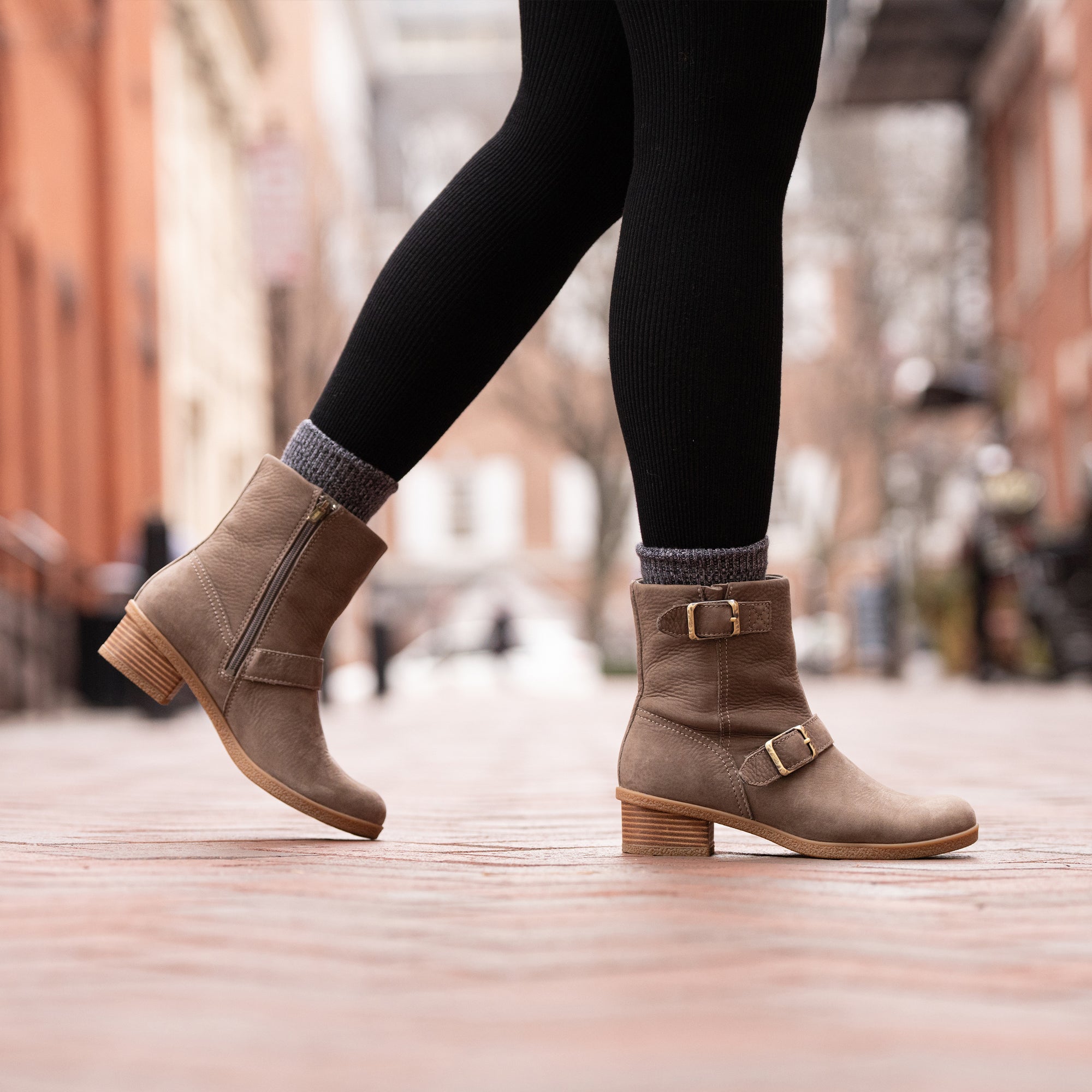 An on-foot look at gray biker booties with fashionable hardware and leather-stacked heels.