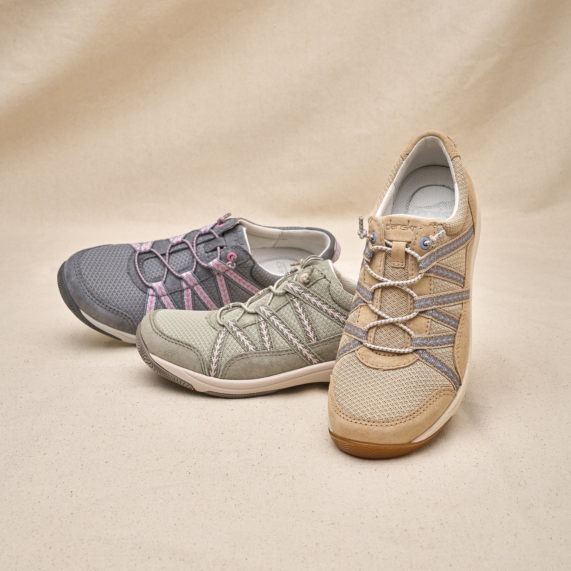 A compact, lightweight sneaker with elastic laces shown in neutrals of gray, ivy, and tan.