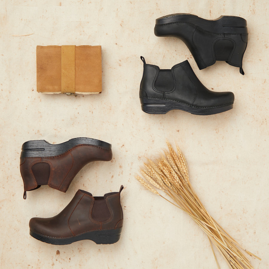 A brown pair of boots and a black pair of boots shown with barn materials.