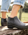 Black boots shown with light denim on a wooden plank.