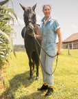 A farmgirl in denim coveralls wearing black boots while working with horses.