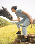 A woman working with a horse and wearing supportive, stylish black boots.