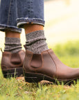 Stylish brown boots shown with grey wool socks and jeans.