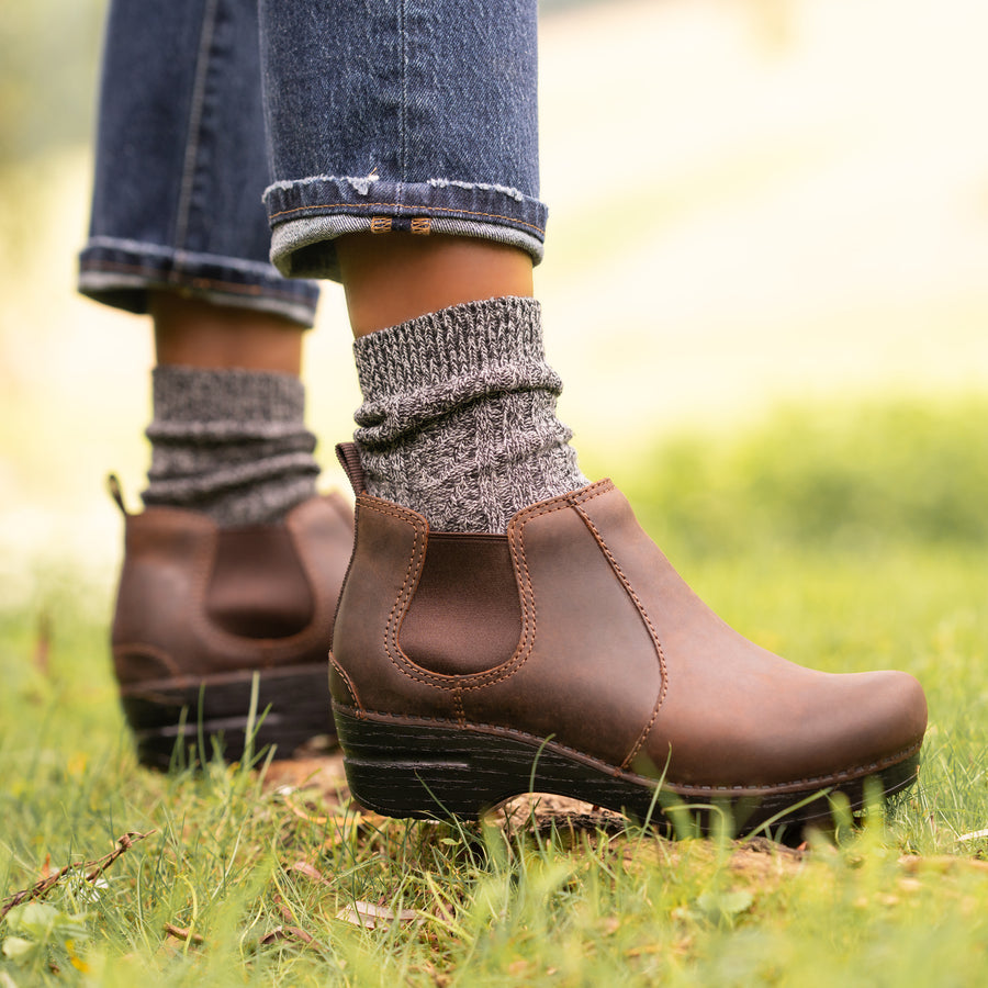 Stylish brown boots shown with grey wool socks and jeans.