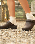 Brown backless clogs with an adjustable swivel strap styled with scalloped white socks.