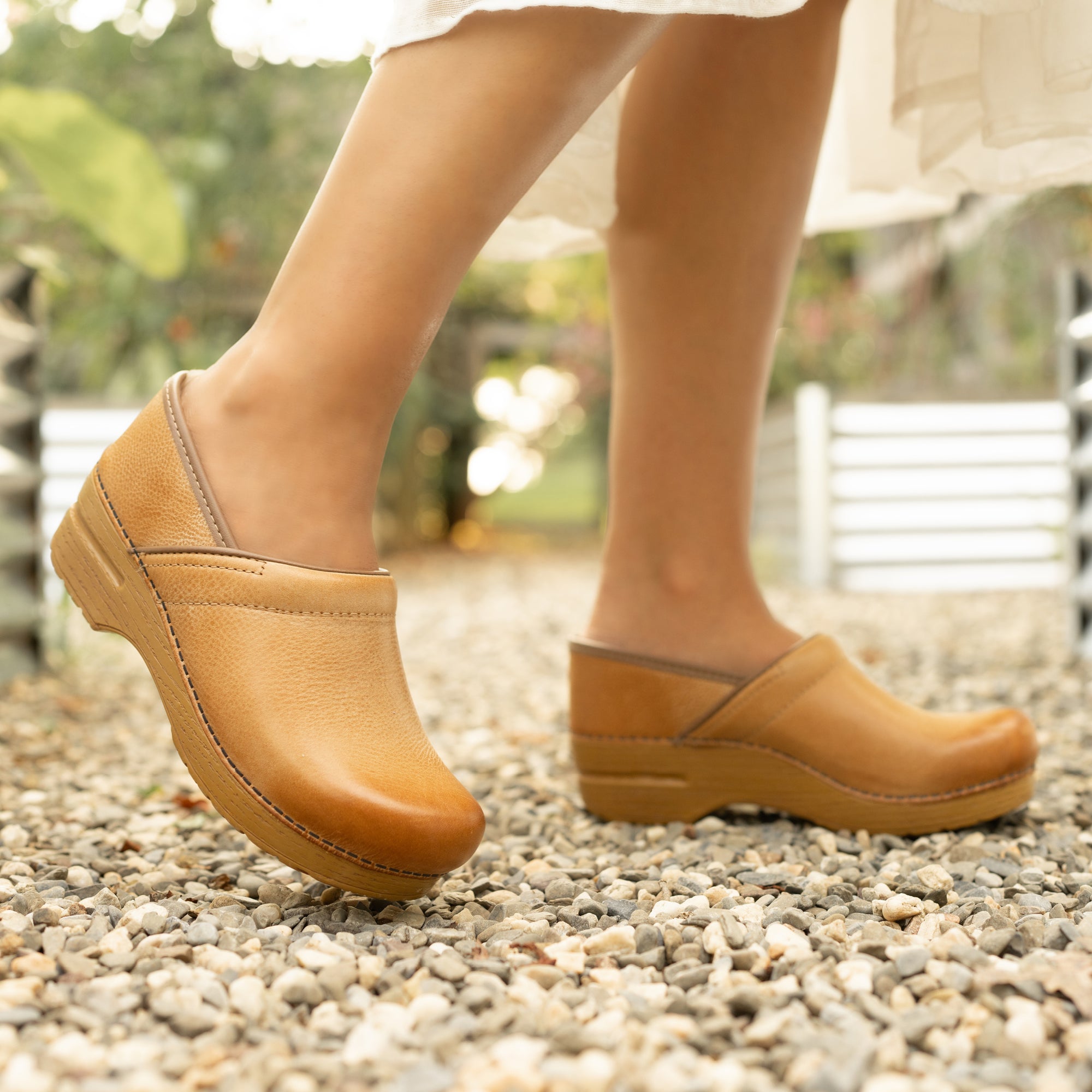Light brown clogs shown in playful motion.