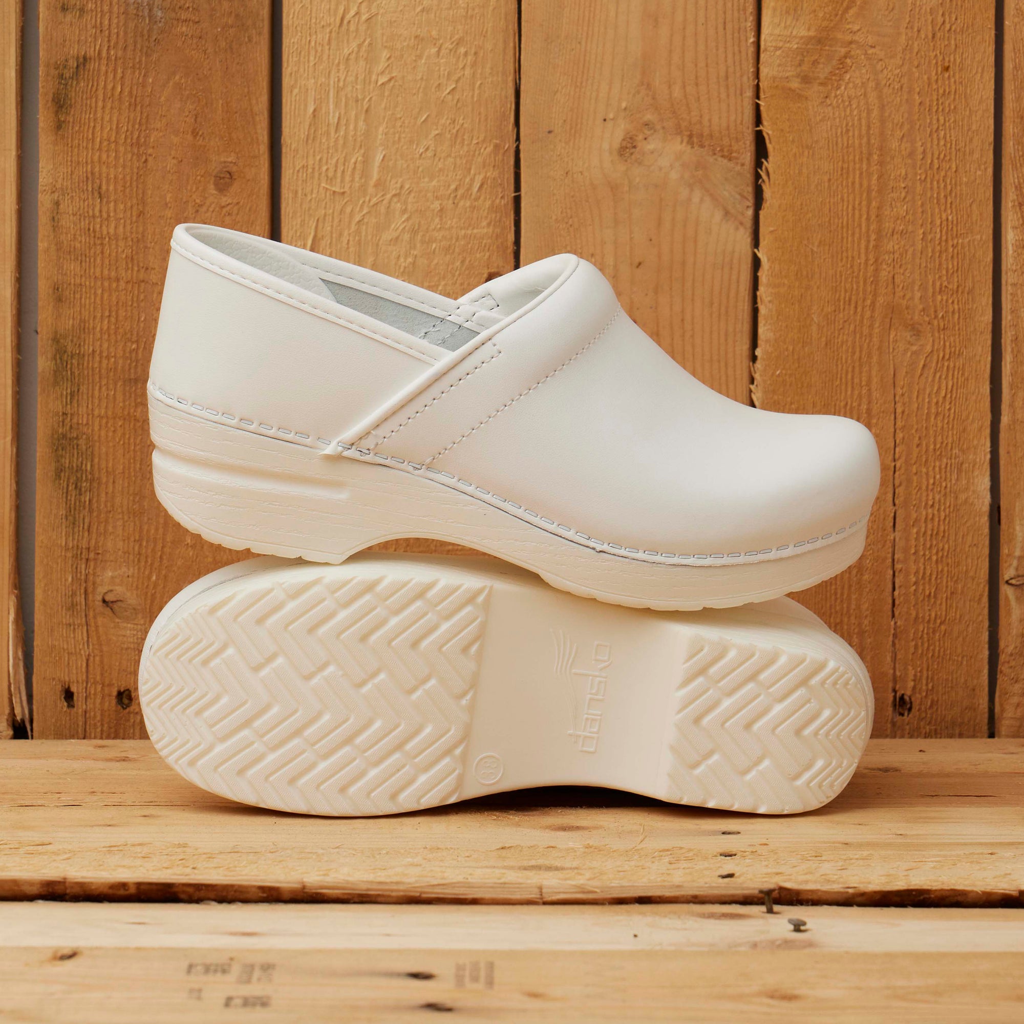 Traditional white clogs shown in front of a wood background.