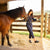 Horse trainer in blue coveralls admiring the comfort of her black mule clogs from Dansko.