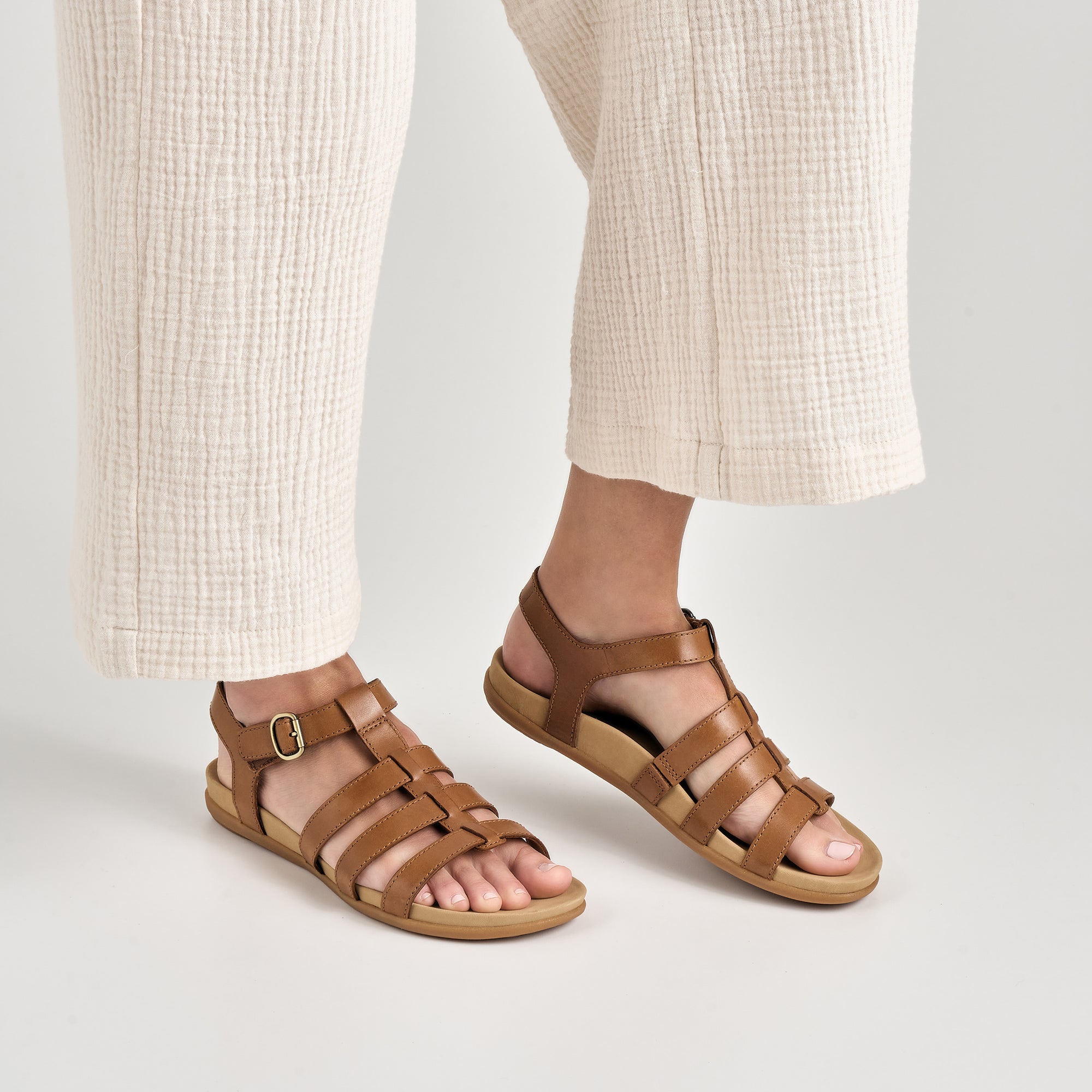 Close up of tan strappy flat sandals.