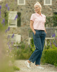 A woman in a garden wearing white leather sneakers with stylish accents.