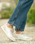 A pair of white leather sneakers with casual accents shown on foot.
